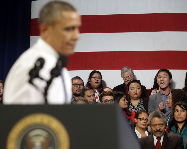 En esta foto del 25 de noviembre de 2013, el presidente estadounidense Barack Obama interrumpe su discurso y se vuelve en respuesta a un hombre no identificado, derecha, que le lanzaba preguntas sobre sus pol&iacute;ticas contra la deportaci&oacute;n. (AP
