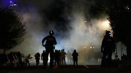 Policías montan guardia tras lanzar gases lacrimógenos afuera de unas instalaciones del Servicio de Inmigración y Control de Aduanas, el sábado 4 de octubre de 2025, en Portland, Oregon. (AP foto/Jenny Kane)