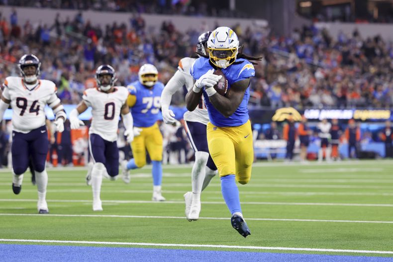 Gus Edwards (4), de los Chargers de Los Ángeles, anota un touchdown por la vía terrestre durante la segunda mitad del partido de la NFL en contra de los Broncos de Denver, el jueves 19 de diciembre de 2024, en Inglewood, California. (AP Foto/Ryan Sun)