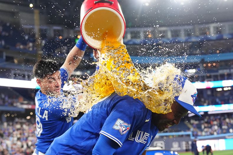 Brandon Valenzuela, de los Azulejos de Toronto, vacía la hielera encima del dominicano Jesús Sánchez, tras la victoria sobre los Marlins de Miami, el martes 26 de mayo de 2026 (Frank Gunn/The Canadian Press via AP)