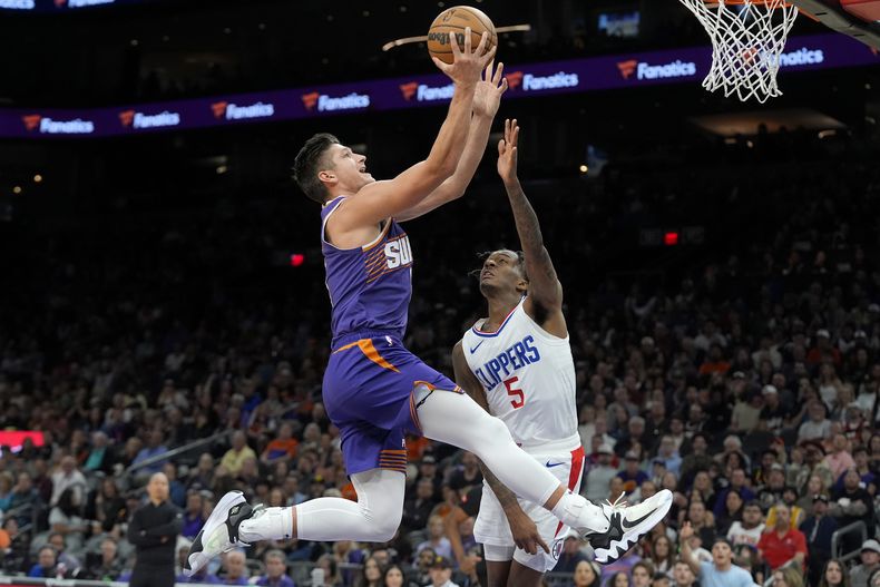 El base de los Suns de Phoenix Grayson Allen avanza para anotar superando al base de los Clippers de Los Ángeles Bones Hyland en el encuentro del martes 9 de abril del 2024. (AP Foto/Ross D. Franklin)