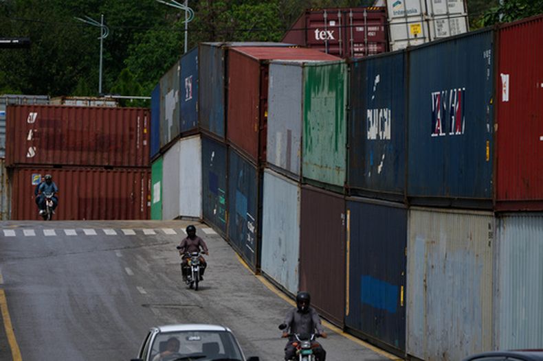 Motoristas pasan junto a contenedores de carga colocados por las autoridades para sellar una zona antes de una marcha de partidarios del ex primer ministro encarcelado Imran Khan, en Islamabad, Pakistán, el lunes 28 de septiembre de 2026. (Foto AP/Anjum Naveed)