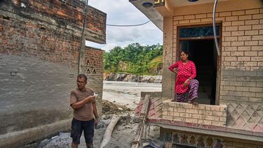 Narayan Prasad Nepal (izquierda), en el exterior de su casa, dañada por una inundación repentina, en Galchi, Nuwakot, Nepal, el 23 de septiembre de 2026. (AP Foto/Niranjan Shrestha)