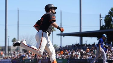 J.D. Davis, de los Gigantes de San Francisco, rodean las bases después de batear un jonrón de tres carreras en contra del abridor de los Rangers de Texas, Adrian Sampson, al fondo, durante la segunda entrada del juego de béisbol del viernes 1 de marzo de 2024, en Scottsdale, Arizona. (AP Foto/Ross D. Franklin)