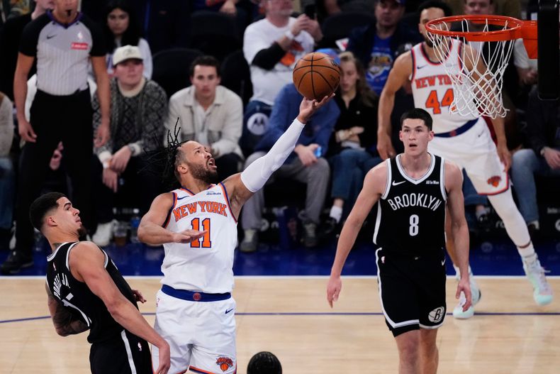 Jalen Brunson (11), de los Knicks de Nueva York, alista una bandeja superando a Michael Porter Jr. (17) y ante la mirada de Egor Dëmin (8), de los Nets de Brooklyn, durante la primera mitad del juego de baloncesto de la NBA, el domingo 9 de noviembre de 2025, en el Madison Square Garden de Nueva York. (AP Foto/Frank Franklin II)