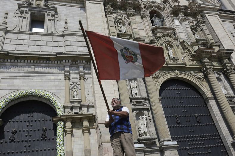 Un hombre ondea una bandera peruana frente a la Catedral después de que el cardenal Robert Prevost fuera elegido como el nuevo papa tomando el nombre de León XIV en Lima, Perú, el jueves 8 de mayo de 2025. (AP Foto/César Zamalloa)