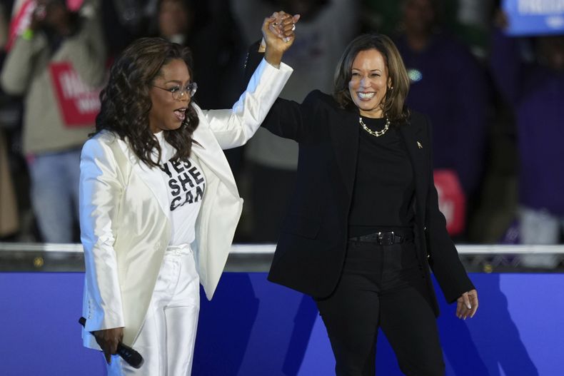 Oprah Winfrey levanta el brazo de la candidata demócrata a la presidencia de Estados Unidos, la vicepresidenta Kamala Harris, tras presentar su intervención en un acto de campaña en el exterior del Museo de Arte de Filadelfia, el 4 de noviembre de 2024, en Filadelfia. (AP Foto/Matt Slocum)