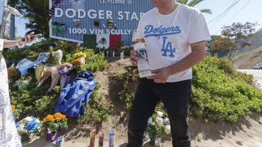 Rafael Gómez, inmigrante salvadoreño, enciende una vela en un altar improvisado afuera del Dodger Stadium en memoria del exlanzador mexicano Fernando Valenzuela, el miércoles 23 de octubre de 2024 (AP Foto/Damian Dovarganes)