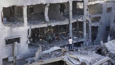 Palestinos buscan entre los escombros de un edificio destruido en el que murió la familia Muharib durante un bombardeo israelí, el jueves 23 de noviembre de 2023, en el campamento de refugiados Nusseirat, en la Franja de Gaza. (AP Foto/Adel Hana)