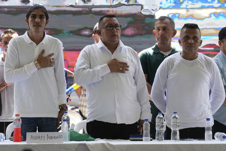 Andrey Avendaño, izquierda; Franco Ramírez, al centro, y Javier 33, derecha, miembros del Estado Mayor Central, escuchan el himno nacional durante conversaciones de paz con el gobierno colombiano, el domingo 8 de octubre de 2023, en Tibú, Colombia. El grupo es una facción armada que se escindió de las Fuerzas Armadas Revolucionarias de Colombia y nunca firmó el acuerdo de paz de 2016 con el gobierno. El jefe de negociación del gobierno, Camilo González Posso, aseguró el miércoles 15 de noviembre en video que retomarán las reuniones con el autodenominado Estado Mayor Central, suspendidas hace dos semanas. (AP Foto/Fernando Vergara)