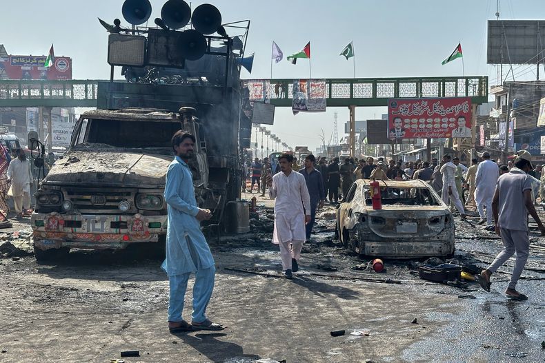 Vecinos de pie entre edificios quemados después de que la policía en Pakistán chocara con miles de manifestantes durante una marcha en apoyo de los palestinos, en Muridke, cerca de Lahore, Pakistán, el lunes 13 de octubre de 2025. (AP Foto/Jahanzeb Khan)