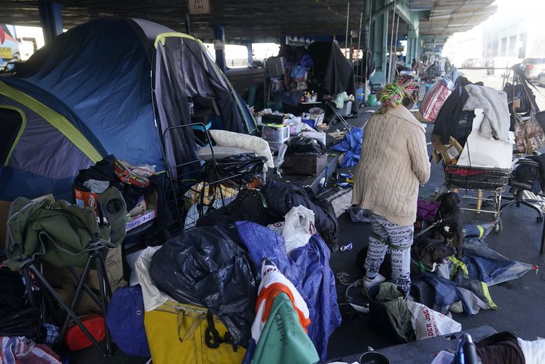 ARCHIVO - Una mujer recoge sus pertenencias antes de las tareas de retiro de un campamento de desamparados en San Francisco, el 29 de agosto de 2023. (AP Foto/Jeff Chiu, archivo)