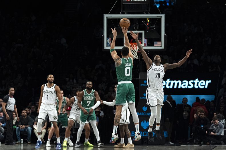 El alero de los Celtics de Boston Jayson Tatum (0) lanza ante el alero de los Nets de Brooklyn Dorian Finney-Smith (28) durante la primera mitad del juego de baloncesto de la NBA en Nueva York, el martes 13 de febrero de 2024. (AP Foto/Peter K. Afriyie)