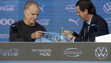 El presidente de la Asociación Uruguaya de Fútbol, Ignacio Alonso (derecha), le entrega la camiseta de la selección al nuevo técnico Marcelo Bielsa durante una rueda de prensa, el miércoles 17 de mayo de 2023, en Montevideo. (AP Foto/Santiago Mazzarovich)