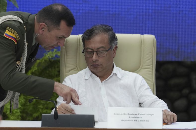 El presidente de Colombia, Gustavo Petro, escucha a un colaborador militar durante la ceremonia de firma de un acuerdo de alto el fuego bilateral entre su gobierno y la guerrilla del Ejército de Liberación Nacional (ELN) de Colombia, en El Laguito, en La Habana, Cuba, el viernes 9 de junio de 2023. (Foto AP/Ramón Espinosa)