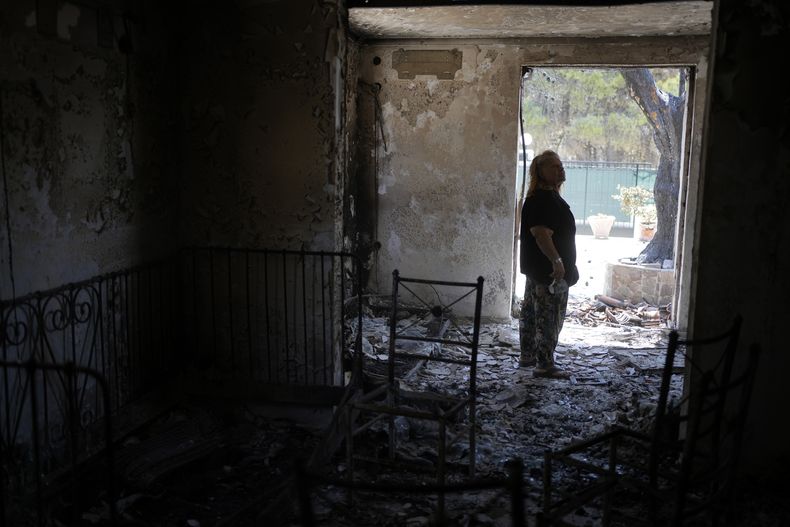 La jubilada Chrysoula Renieri visita su casa quemada por los incendios forestales en Loutraki, Grecia, el 22 de julio de 2023. (Foto AP/Thanassis Stavrakis)