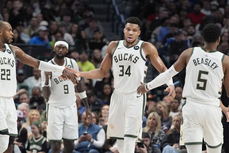 El alero de los Bucks de Milwaukee, Giannis Antetokounmpo (34), es felicitado por sus compañeros de equipo Khris Middleton (22) y Malik Beasley (5) después de encestar un tiro libre durante la segunda mitad del partido de baloncesto de la NBA contra los Mavericks de Dallas, el sábado 3 de febrero de 2024. (AP Foto/LM Otero)