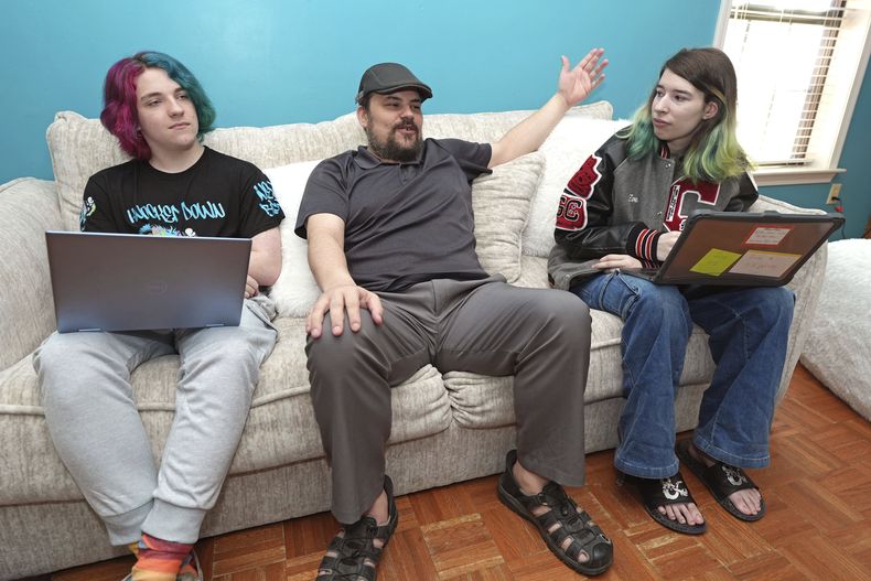 Tim Reiland, de 42 años, junto con sus hijos Zoe Reiland, de 17 años, a la derecha, y Anakin Reiland, de 15, fotografiados en Clinton, Mississippi, el lunes 10 de marzo de 2025, platoca sobre el uso tecnología de vigilancia para monitorear a los estudiantes. (AP Foto/Rogelio V. Solís)