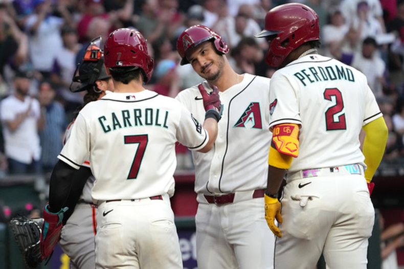 Nolan Arenado, segundo desde la derecha, de los Diamondbacks de Arizona, celebra con Corbin Carroll (7) y Geraldo Perdomo (2) después de batear un grand slam contra los Gigantes de San Francisco, en la primera entrada, el lunes 18 de mayo de 2026, en Phoenix. (AP Foto/Rick Scuteri)