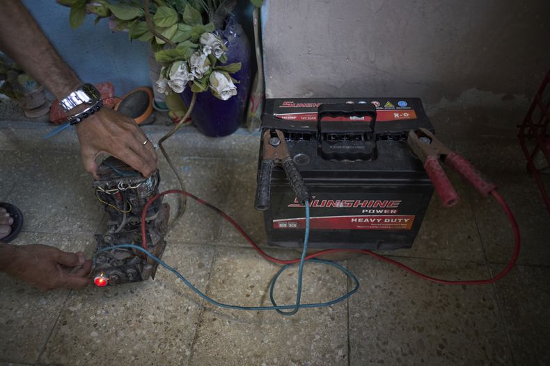 Ángel Rodríguez usa un transformador de una vieja televisión para cargar una batería ante los apagones de luz en su casa en el barrio de Bahía en La Habana, Cuba, el lunes 26 de mayo de 2025. (AP Foto/Ramón Espinosa)
