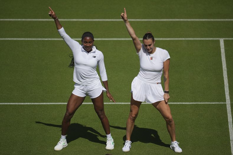 Aryna Sabalenka de Bielorrusia, derecha, y Coco Gauff de Estados Unidos bailan durante una sesión de práctica previa al Campeonato de Wimbledon en Londres, el viernes 27 de junio de 2025. (AP Photo/Kin Cheung)