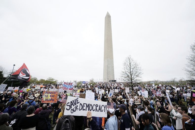 Manifestantes sostienen carteles durante una protesta de ¡Manos fuera! contra el presidente Donald Trump en el Monumento a Washington en Washington, el sábado 5 de abril de 2025. (AP foto/Jose Luis Magana)