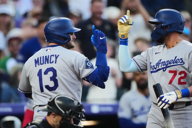 Miguel Rojas, derecha, de los Dodgers de Los Ángeles, felicita a Max Muncy (13) después del jonrón solitario de Muncy frente al abridor de los Rockies de Colorado, José Quintana, en la segunda entrada del juego de béisbol de Grandes Ligas, el lunes 20 de abril de 2026. en Denver. (AP Foto/David Zalubowski)