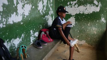 Yeferson Seijas se pone sus zapatos deportivos para un entrenamiento de béisbol en La Guaira, Venezuela, el sábado 11 de julio de 2026, después de que los sismos dejaran a su familia sin hogar, y de que algunos de los niños con los que creció jugando acabaran lesionados, huérfanos, muertos o desaparecidos. (AP Foto/Ariana Cubillos)