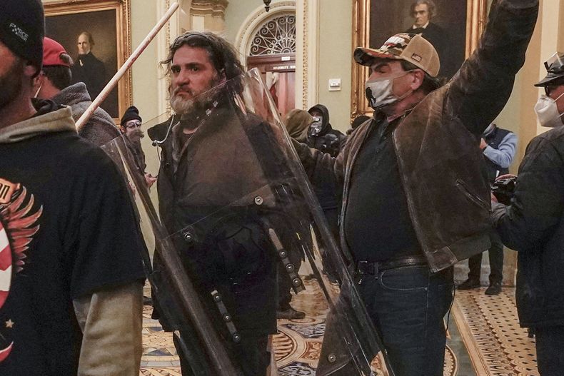 ARCHIVOS - Dominic Pezzola, centro con escudo policial, y otros insurrectos enfrentan a agentes de la Policía del Capitolio frente al recinto del Senado en el Capitolio, 6 de enero de 2021. Pezzola, exmiembro de la milicia de ultraderecha Proud Boys que rompió una ventana del Capitolio durante la insurrección, fue condenado a 10 años de prisión el viernes 1 de setiembre de 2023. (AP Foto/Manuel Balce Ceneta, File)