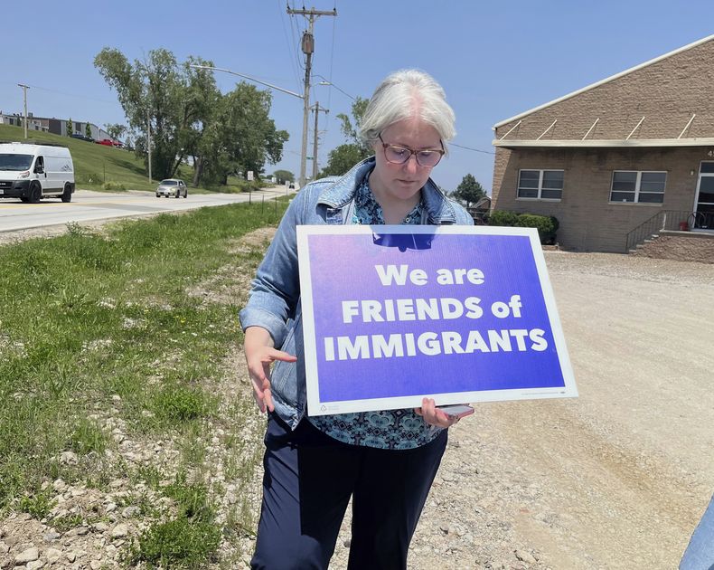 Sara Schulte-Bukowinski, líder religiosa de Omaha, Nebraska, sostiene un cartel de protesta contra una redada de inmigración, el martes 10 de junio de 2025, en Glenn Valley Foods, una empacadora de carne del sur de Omaha. (AP Foto/Margery A. Beck)