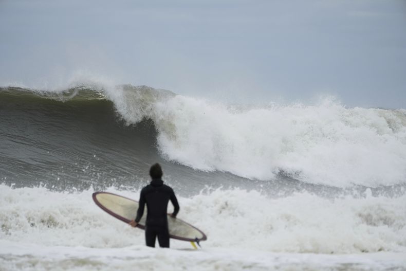 Un surfista trata de llegar al agua frente a las grandes olas provocadas por el huracán Erin, en Rockaway Beach, en el distrito neoyorquino de Queens, el jueves 21 de agosto de 2025. (AP Foto/Seth Wenig)