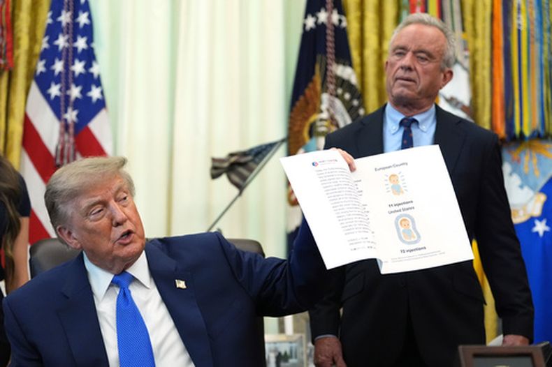 El presidente estadounidense Donald Trump sostiene una imagen tomada de su cuenta en Truth Social con el secretario de Salud y Servicios Humanos, Robert F. Kennedy Jr., durante una reunión para firmar una orden ejecutiva sobre vacunación, el lunes 10 de agosto de 2026, in en el Despacho Oval de la Casa Blanca, en Washington. (AP Foto/Jacquelyn Martin)