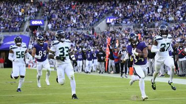 Keaton Mitchell (34), corredor de los Ravens de Baltimore, se escapa del safety Jamal Adams (33) y el cornerback Riq Woolen (27), de los Seahawks de Seattle, durante un acarreo de anotación de 40 yardas en la segunda mitad del partido de la NFL, el domingo 5 de noviembre de 2023, en Baltimore. (AP Foto/Nick Wass)