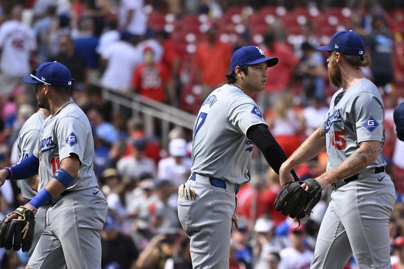 El bateador designado de los Dodgers de Los Ángeles, Shohei Ohtani (centro) felicita al relevista Michael Kopech (derecha) luego de vencer a los Cardenales de San Luis, el domingo 18 de agosto de 2024, en San Luis. (AP Foto/Jeff Le)