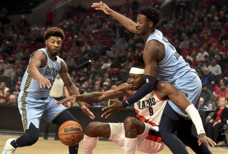 Jerami Grant, centro, de los Trail Blazers de Portland, y Jaren Jackson Jr., derecha, de los Grizzlies de Memphis, disputan un balón mientras Marcus Smart, izquierda, se acerca para pelearlo, durante la primera mitad del juego de baloncesto de la NBA, en Portland, Oregon, el domingo 5 de noviembre de 2023. (AP Foto/Steve Dykes)