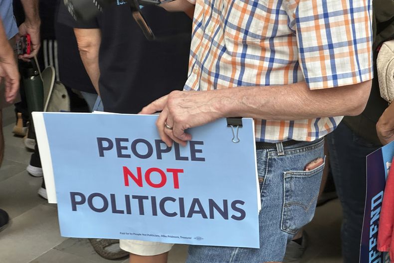 Un manifestante sostiene un cartel en oposición al plan para redistribuir los distritos de Missouri en la Cámara de Representantes de Estados Unidos, en una marcha en el Capitolio estatal, el viernes 12 de septiembre de 2025, en Jefferson City, Missouri. (AP Foto/David A. Lieb)