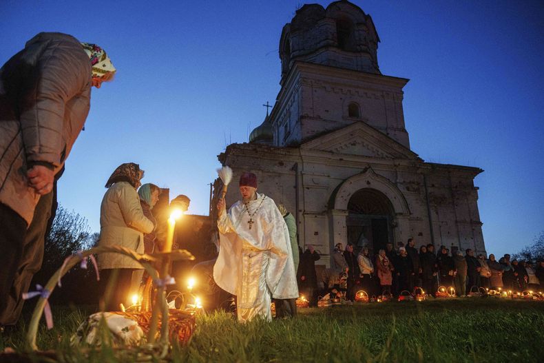 El sacerdote Serhii Zezul bendice cestas de Pascua ante una iglesia destruida en los combates entre fuerzas rusas y ucranianas, durante una celebración de la Pascua Ortodoxa en Lukashivka, Ucrania, el domingo 20 de abril de 2025. (AP Foto/Evgeniy Maloletka)