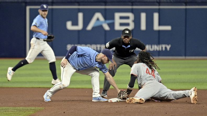 El campocorto de los Rays de Tampa Bay, Taylor Walls (izquierda) y el árbitro Edwin Moscoso (centro) observan al dominicano de los Rojos de Cincinnati, Elly De La Cruz llegar antes que Brandon Lowe para un robo de base durante la sexta entrada del juego de béisbol, el domingo 28 de julio de 2024, en San Petersburgo, Florida. (AP Foto/Steve Nesius)