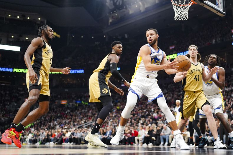 Stephen Curry, base de los Warriors de Golden State, trata de avanzar ante Immanuel Quickley (izquierda), RJ Barrett y Kelly Olynyk (41), de los Raptors de Toronto, en el duelo del viernes 1 de marzo de 2024 (Arlyn McAdorey/The Canadian Press via AP)