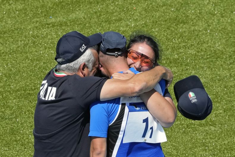 Los italianos Diana Bacosi (derecha), Gabriele Rossetti (centro) y su entrenador se abrazan tras ganar la medalla de oro en la final del skeet mixto del tiro de los Juegos Olímpicos de París, el lunes 5 de agosto de 2024, en Chateauroux, Francia. (AP Foto/Manish Swarup)