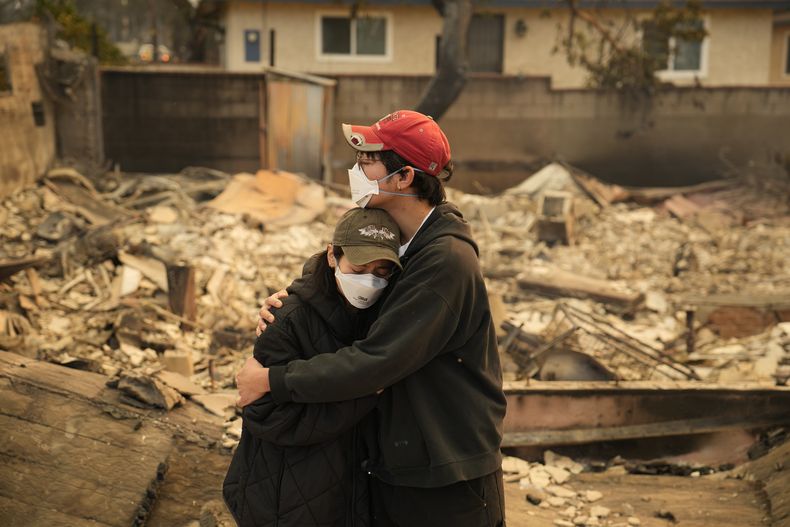 Ari Rivera (derecha) y Anderson Hao se abrazan frente a su casa destrozada en Altadena, California, el jueves 9 de enero de 2025. (AP Foto/John Locher)