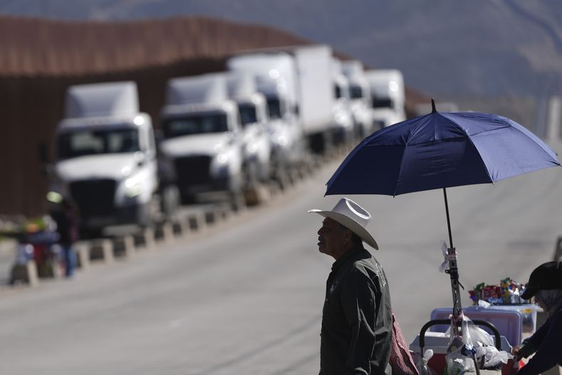 Susano Córdoba vende maní a camioneros que hacen fila para cruzar la frontera hacia Estados Unidos en un momento en que los aranceles contra México entran en vigencia, el martes 4 de marzo de 2025, en Tijuana, México. (AP Foto/Gregory Bull)