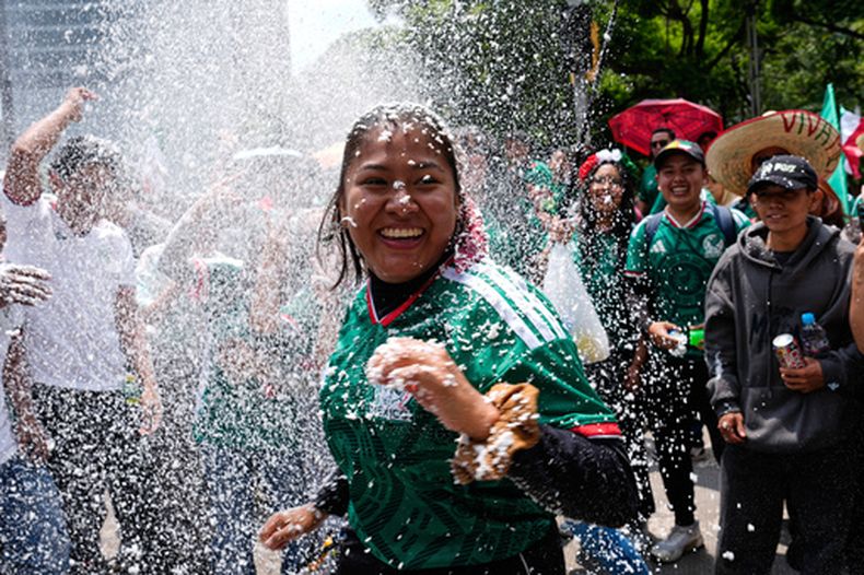Aficionados mexicanos se lanzan espuma en la capital de su país, donde miran en pantalla gigante el partido del Mundial ante Ecuador, el martes 30 de junio de 2026 (AP Foto/Marco Ugarte)