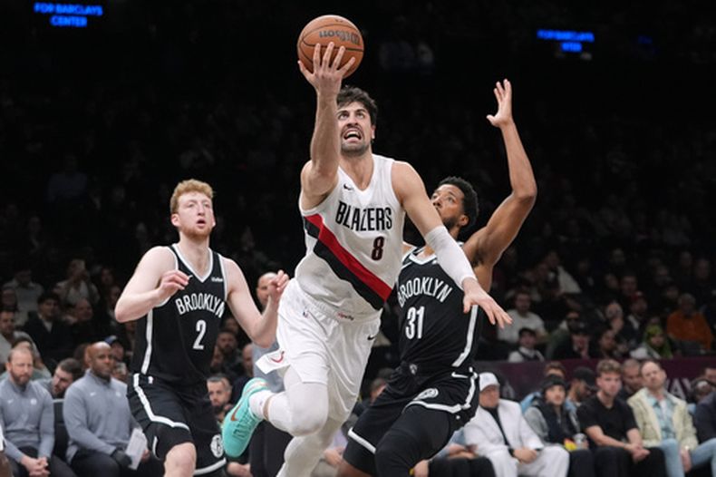 Deni Avdija (8), de los Trail Blazers de Portland, pasa entre Danny Wolf (2) y Chaney Johnson (31), de los Nets de Brooklyn, para encestar durante la segunda mitad del juego de baloncesto de la NBA del lunes 16 de marzo de 2026, en Nueva York. (AP Foto/Frank Franklin II)