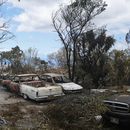Vehículos calcinados se ven junto a una casa destruida por los incendios el lunes 14 de agosto de 2023, en Kula, Hawai. El mismo día que un incendio devastó la localidad de Lahaina, otro golpeó la población de Kula. (AP Foto/Rick Bowmer)