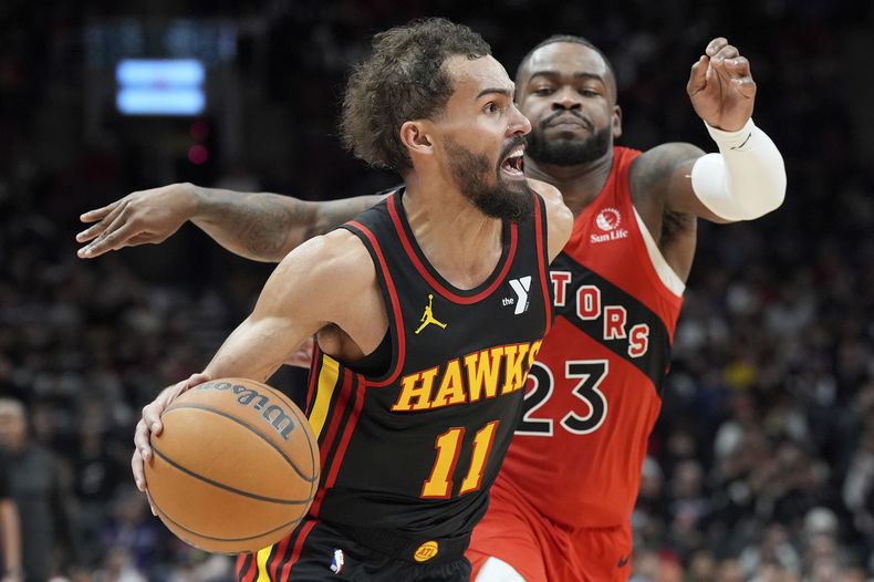 Trae Young (11), de los Hawks de Atlanta, se enfila con el balón hacia la canasta, dejando atrás la marca defensiva de Jamal Shead (23), de los Raptor de Toronto, en el juego de baloncesto de la NBA del domingo 29 de diciembre de 2024, en Toronto. (Frank Gunn/The Canadian Press vía AP)