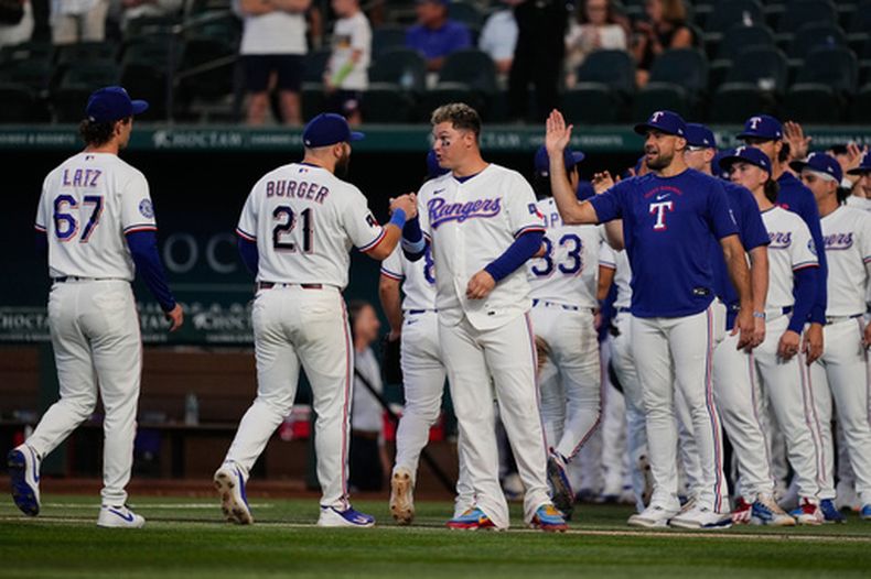 Jacob Latz (67), Jake Burger (21), Joc Pederson (centro), Nathan Eovaldi (derecha) y el resto de los Rangers de Texas tras su victoria sobre los Marineros de Seattle, el lunes 27 de julio de 2026, en Arlington, Texas. (AP Foto/Tony Gutiérrez)