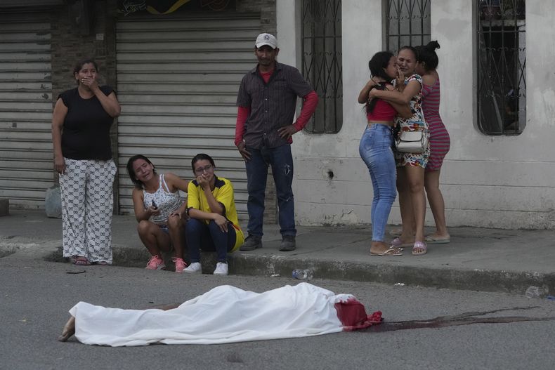 Varias personas lloran junto al cadáver de un hombre, asesinado en circunstancias desconocidas, en una calle de Durán, Ecuador, el 21 de julio de 2023, en medio de una ola de violencia que las autoridades atribuyen a la lucha de territorio entre bandas del crimen organizado. (AP Foto/Dolores Ochoa)