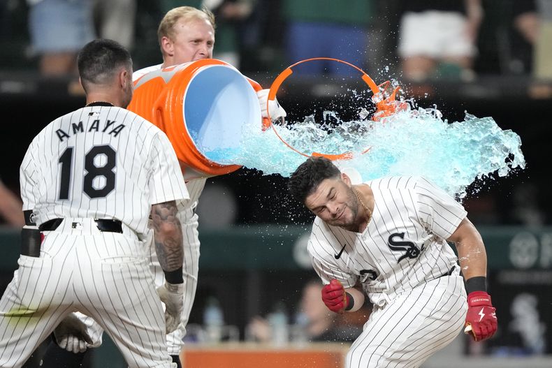 Andrew Vaughn, centro, de los Medias Blancas de Chicago, baña a Andrew Benintendi después del jonrón ganador de Benintendi en la novena entrada contra los Atléticos de Oakland el sábado 14 de septiembre de 2024, en Chicago. (AP Foto/Charles Rex Arbogast)