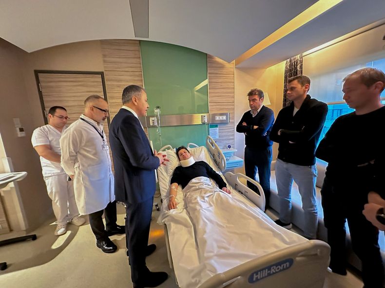 En esta imagen distribuida por el Ministerio del Interior, el árbitro turco Halil Umut Meler (centro), descansa en una cama mientras habla con el ministro del Interior, Ali Yerlikaya (tercero por la izquierda), en el hospital Acibadem, en Ankara, el 12 de diciembre de 2023. (Ministerio del Interior de Turquía vía AP)